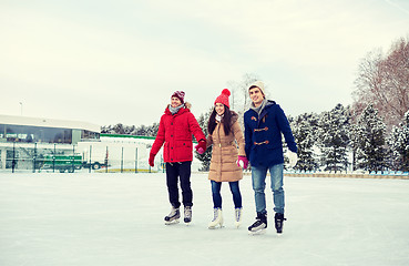 Image showing happy friends ice skating on rink outdoors