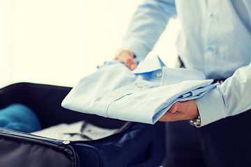 Image showing businessman packing clothes into travel bag