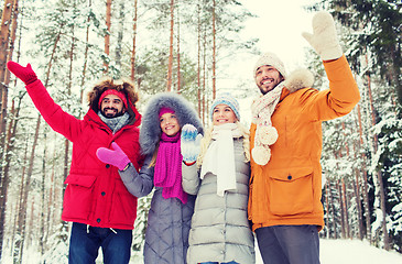 Image showing group of friends waving hands in winter forest