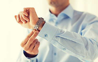 Image showing close up of man in shirt fastening wristwatch