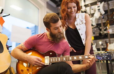 Image showing couple of musicians with guitar at music store