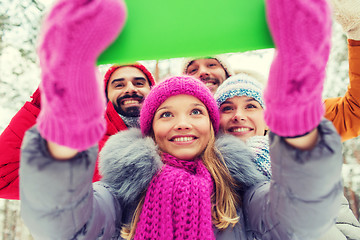 Image showing smiling friends with tablet pc in winter forest