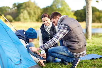 Image showing happy parents and son setting up tent outdoors