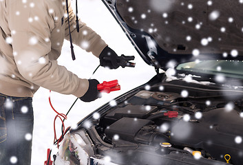 Image showing closeup of man under bonnet with starter cables