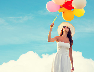 Image showing smiling young woman in sunglasses with balloons