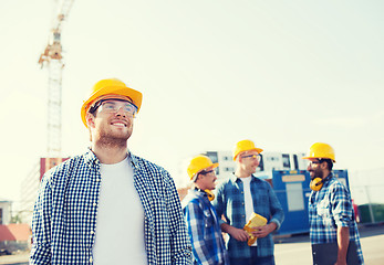 Image showing group of smiling builders in hardhats outdoors