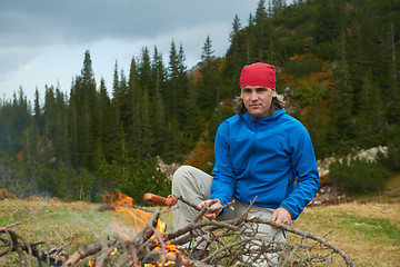 Image showing hiking man prepare tasty sausages on campfire