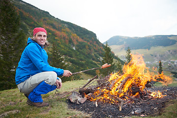 Image showing hiking man prepare tasty sausages on campfire