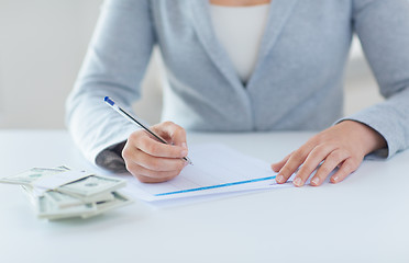 Image showing close up of hands with money filling tax form