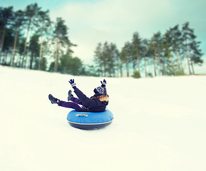 Image showing happy young man sliding down on snow tube