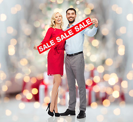 Image showing happy couple with sale sign over christmas lights