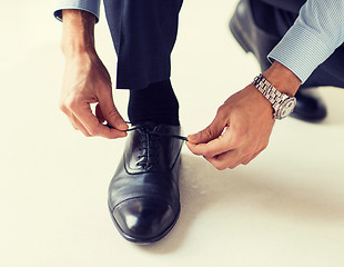 Image showing close up of man leg and hands tying shoe laces