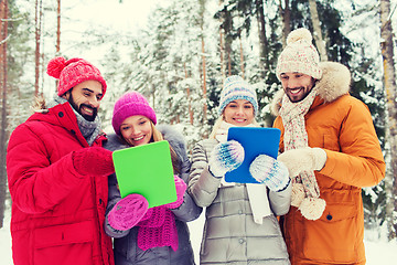 Image showing smiling friends with tablet pc in winter forest