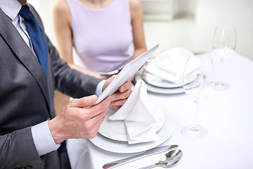 Image showing close up of couple with tablet pc at restaurant