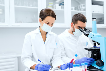 Image showing scientists with clipboard and microscope in lab