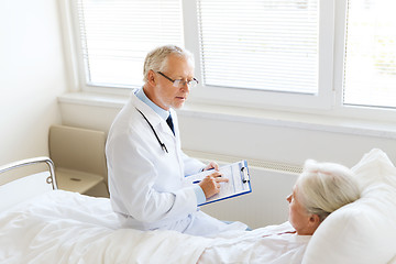 Image showing senior woman and doctor with clipboard at hospital