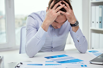 Image showing stressed businessman with papers in office