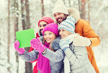 Image showing smiling friends with tablet pc in winter forest