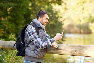 Image showing happy man with backpack and smartphone outdoors