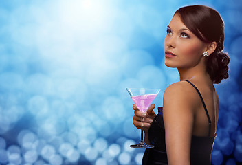 Image showing smiling woman holding cocktail over blue lights