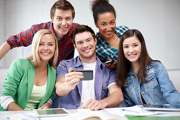 Image showing group of happy students with smartphone at school