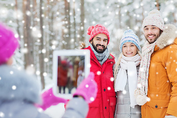 Image showing smiling friends with tablet pc in winter forest