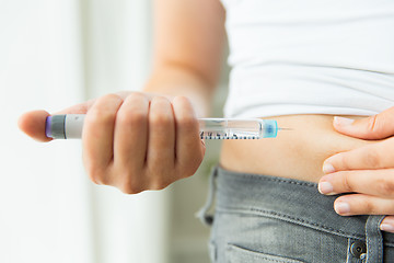 Image showing close up of hands making injection by insulin pen