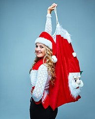 Image showing Girl dressed in santa hat holding a Christmas decoration  