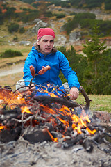 Image showing hiking man prepare tasty sausages on campfire