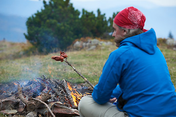 Image showing hiking man prepare tasty sausages on campfire