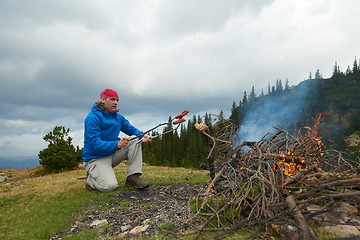 Image showing hiking man prepare tasty sausages on campfire