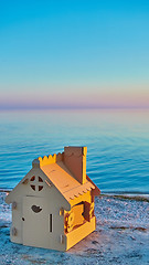 Image showing Toy house made of corrugated cardboard in the sea coast at sunset.