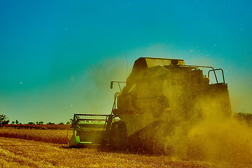 Image showing Harvester combine harvesting wheat on summer day.