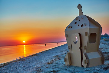 Image showing Cardboard toy spaceship at sea coast and sunset.