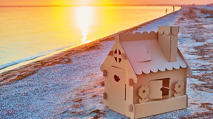 Image showing Toy house made of corrugated cardboard in the sea coast at sunset.