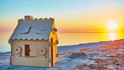 Image showing Toy house made of corrugated cardboard in the sea coast at sunset.