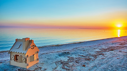 Image showing Toy house made of corrugated cardboard in the sea coast at sunset.