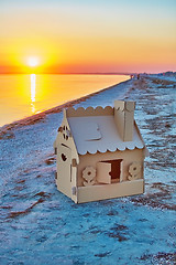 Image showing Toy house made of corrugated cardboard in the sea coast at sunset.