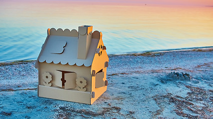 Image showing Toy house made of corrugated cardboard in the sea coast at sunset.