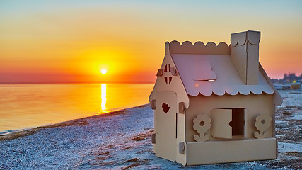 Image showing Toy house made of corrugated cardboard in the sea coast at sunset.