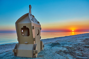 Image showing Cardboard toy spaceship at sea coast and sunset.