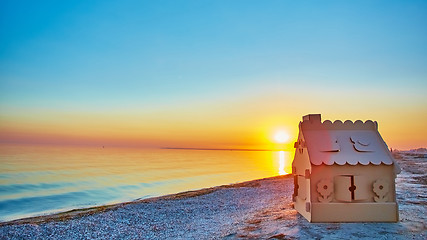 Image showing Toy house made of corrugated cardboard in the sea coast at sunset.