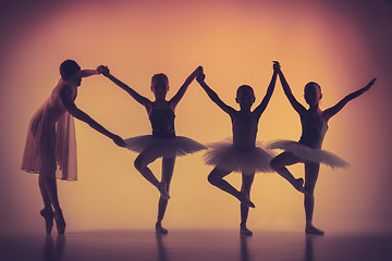 Image showing Three little ballerinas dancing with personal ballet teacher in dance studio