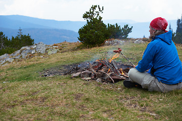 Image showing hiking man prepare tasty sausages on campfire