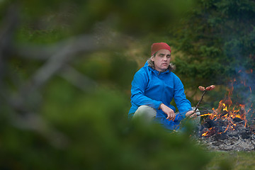 Image showing hiking man prepare tasty sausages on campfire