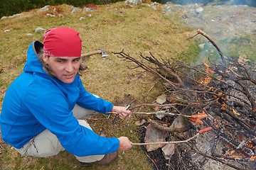 Image showing hiking man prepare tasty sausages on campfire