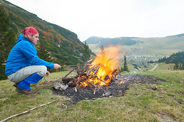 Image showing hiking man prepare tasty sausages on campfire