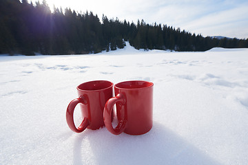 Image showing two red coups of hot tea drink in snow  at winter