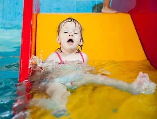 Image showing Pretty little girl rides from hill in aquapark