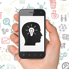 Image showing Business concept: Hand Holding Smartphone with Head With Light Bulb on display